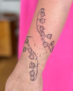 a woman's wrist tattoo with flowers and dots on her left arm, in black ink