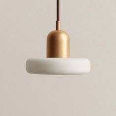 a white and gold colored light hanging from a ceiling fixture in a room with beige walls