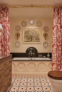 the bathroom is decorated with red and white wallpaper, patterned flooring, an antique bathtub