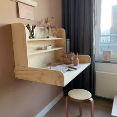 a wooden desk with shelves above it and a chair next to it in front of a window