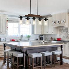 a large kitchen island with stools in the center and lights hanging from it's ceiling