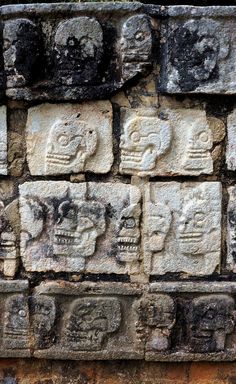 some kind of stone wall with skulls on it's face and faces in the middle