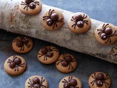 cookies with chocolate spider decorations on them sitting on a piece of wood next to a stick