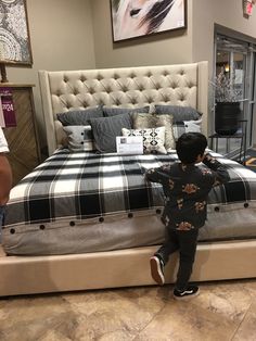 a little boy standing on top of a bed