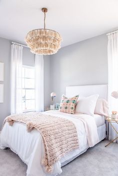 a bedroom with a white bed and a chandelier hanging above the headboard