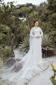 a woman in a white wedding dress standing next to plants