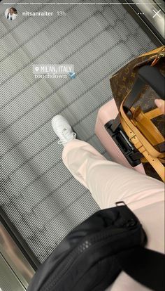 a person sitting on an escalator with their feet up and luggage in the air