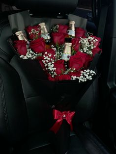 a bouquet of roses in the back seat of a car with bottles of champagne and baby's breath