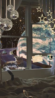 a cat is sitting on a bed looking out the window at the stars and planets