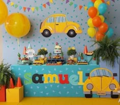 a party with cars and balloons on the wall, table set up for children's birthday