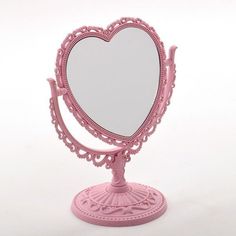 a pink heart shaped mirror sitting on top of a stand