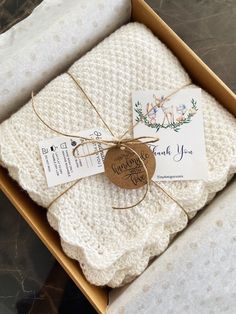 a box with two white blankets and a tag that says thank you on the front