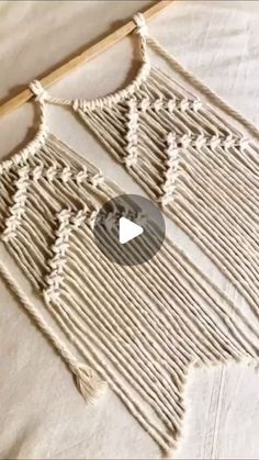 the video shows how to make a woven wall hanging with yarn and wood dows