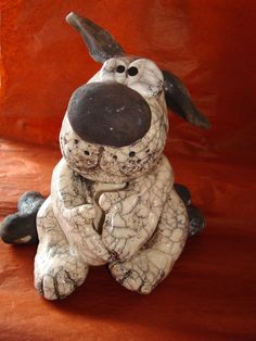 a ceramic dog statue sitting on top of a wooden table next to a red wall