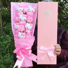 a person holding a hello kitty bouquet in their hand and a pink box with it's contents