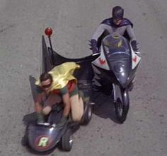 two motorcyclists are riding down the street with their helmets on and one is upside down