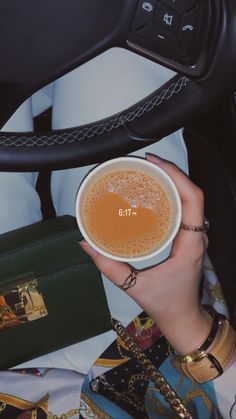 a woman is holding a cup of coffee in her hand while sitting in a car