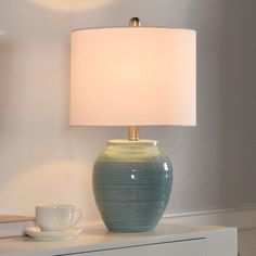 a blue vase sitting on top of a table next to a lamp