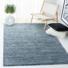 a living room with a chair, rug and plant on the floor in front of a window