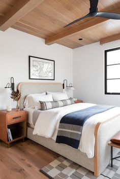 a bedroom with white walls and wood ceilinging, along with a bed that has a blue blanket on it