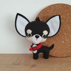 a small black and white dog sitting on top of a wooden table next to a cork circle