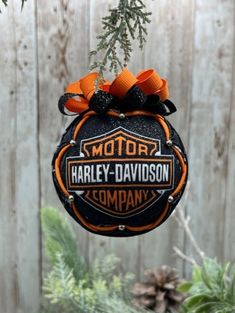 an ornament hanging from a tree in front of a wooden fence with pine cones