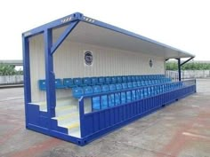 an empty blue and white baseball dugout with steps leading up to the bench area