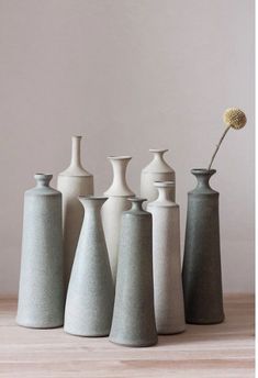 several vases are lined up on a table with a flower in the middle one