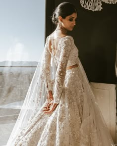 a woman in a wedding dress looking out the window