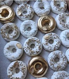 there are many donuts in the box with gold sprinkles on them