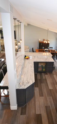 an open kitchen and dining room with wood flooring in the center, along with marble counter tops