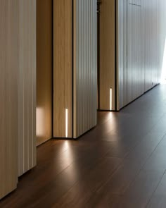 an empty room with wooden floors and white walls, lights on the side of the wall