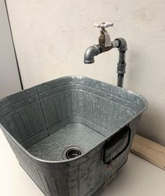 a metal tub sitting next to a faucet on top of a white counter