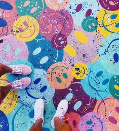 someone standing in front of a colorful floor with smiley faces painted on it and their feet propped up against the ground