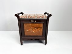 an old fashioned wooden cabinet with a cushion on top