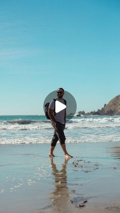 a man is walking on the beach with his surfboard in hand and looking at the water