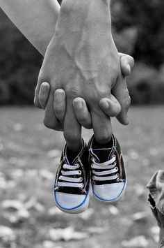 two people holding hands over each other in black and white with leaves on the ground