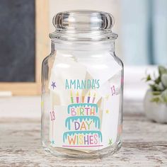 a glass jar filled with birthday wishes on top of a table