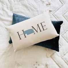 two pillows sitting on top of a bed with the word home printed on them in black and white