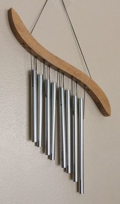 a wind chime hanging from the side of a wall with metal tubes attached to it