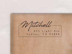 a brown envelope with a black ink stamp on it and the words mitchell in cursive writing