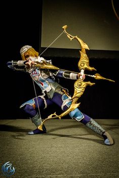 a woman dressed in armor holding a bow and arrow