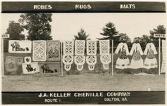 an old black and white photo of quilts hanging on a fence with trees in the background