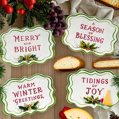 four christmas coasters on a table with cheese, bread and fruit in the background