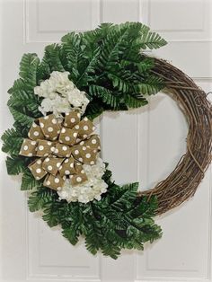 a wreath with white flowers and green leaves hanging on a door handle that is decorated with polka dots