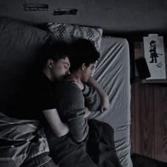 two people are laying on a bed with their arms around each other and one is hugging the other