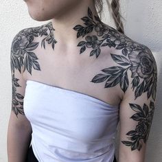 a woman wearing a white top with black flowers on her chest and shoulder tattoo design