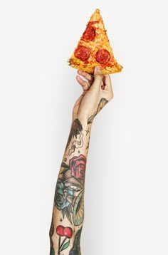 a person holding up a slice of pizza in front of their face with tattoos on it