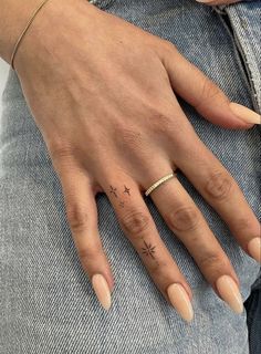 a woman's hand with a small star tattoo on her left thumb and ring