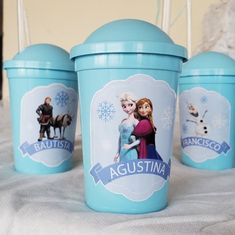 three ice cream cups with frozen princess images on them, sitting on a white blanket